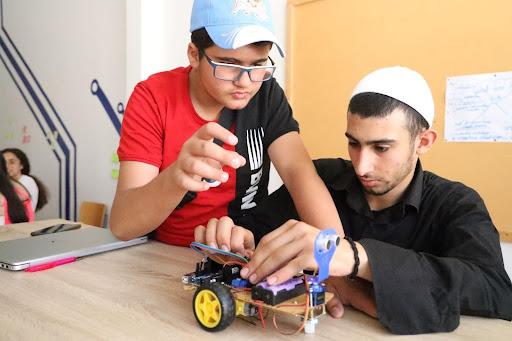 Two teenage boys in hats build a robot vehicle