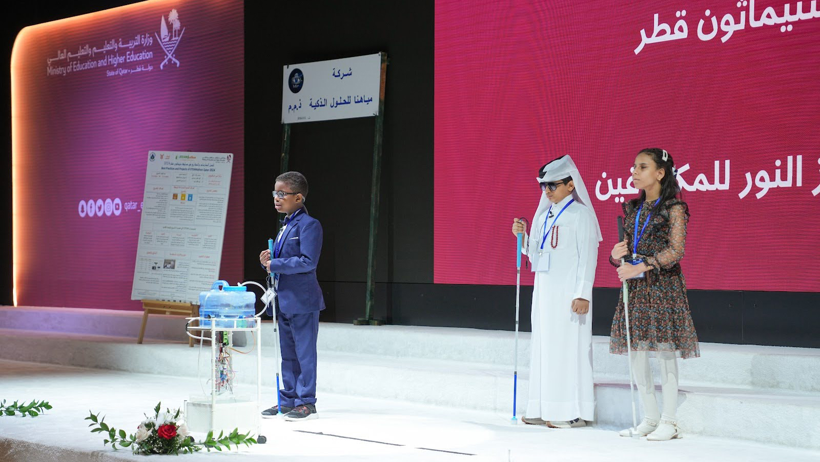 Three young students on a stage
