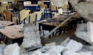A classroom with rubble on the desks