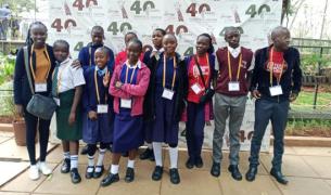 A group of young teenage Kenyan students pose together with their teacher