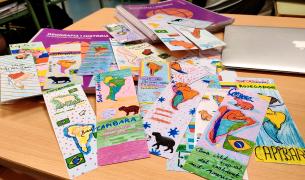 A collection of colorful, hand-drawn maps indicating where capybaras live spread out on a table