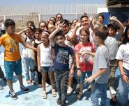 A large group of young Lebanese children pose for a photo in an outdoor courtyard smiling and laughing