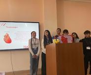 Students stand in front of a screen sharing a presentation about the heart
