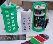 Three 3D-printed CanSat satellite components, labeled "CANSAT KENYA," showing the green outer casing, white inner payload, and internal electronic circuitry.