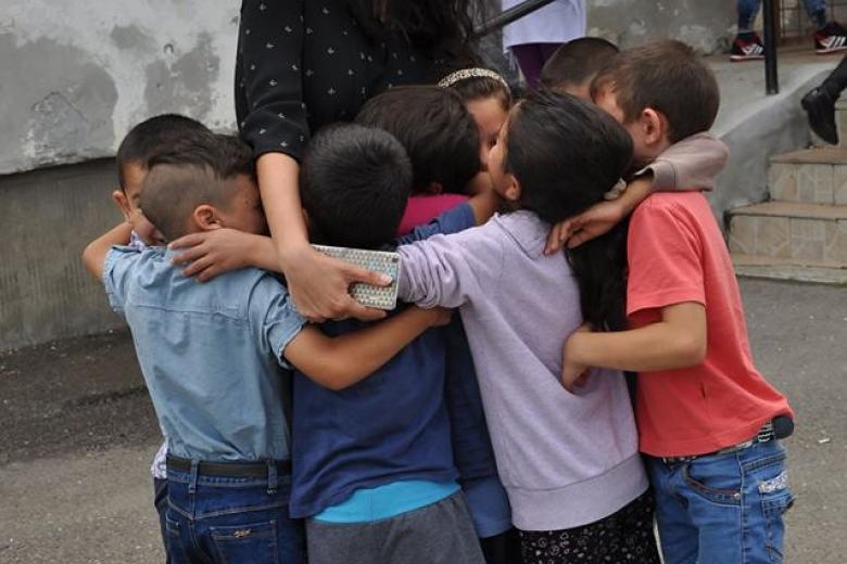Teacher and a group of children in a group hug