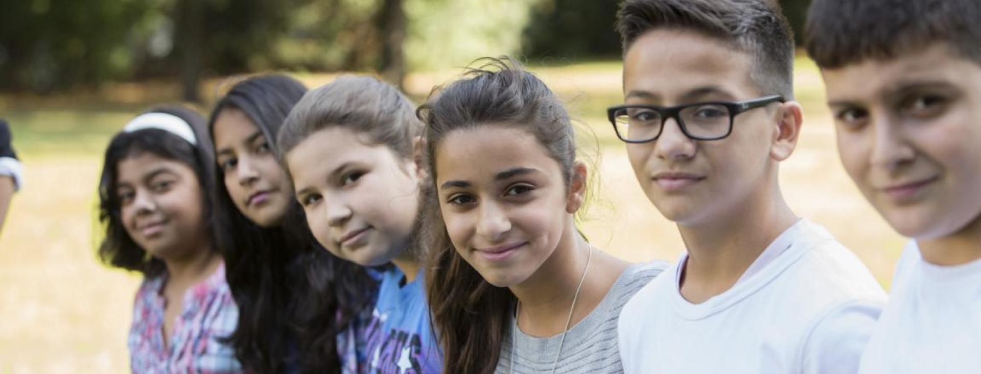 A row of young teens of diverse ethnicities and genders faces the camera