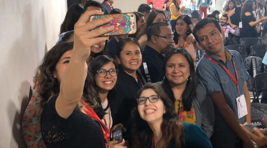 A diverse group of young adults poses for a selfie