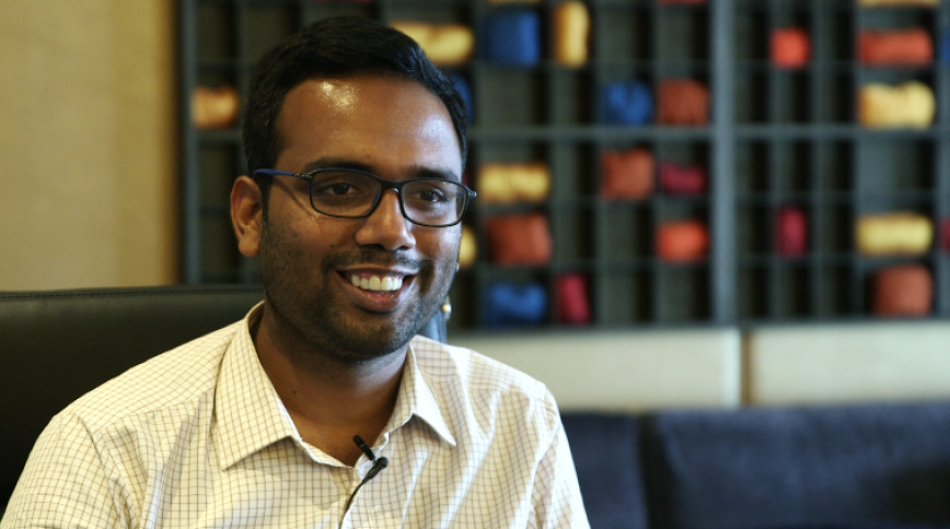 Close up headshot of a young Indian man with short hair and a white collared shirt