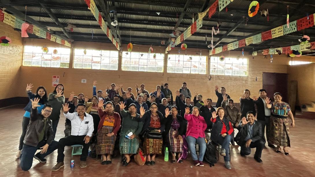 A large group of people pose with their palms raised in reference to the palm on Enseña por Guatemala's logo