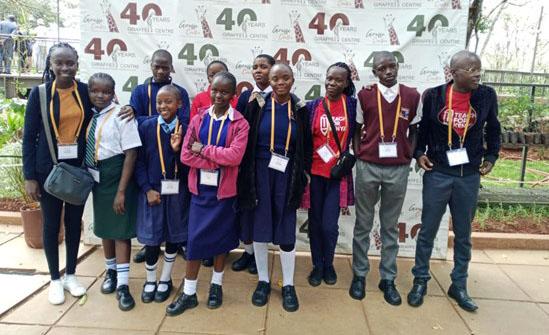 A group of young teenage Kenyan students pose together with their teacher