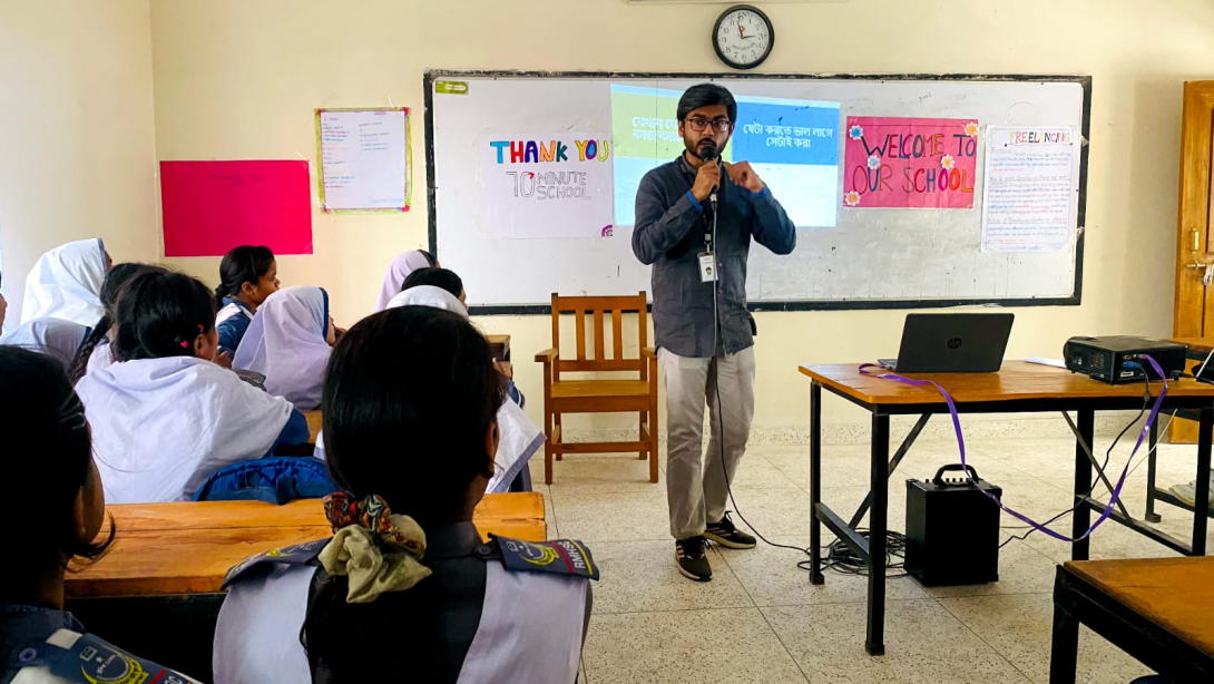 A man representing 10 Minute School presents to a classroom of children