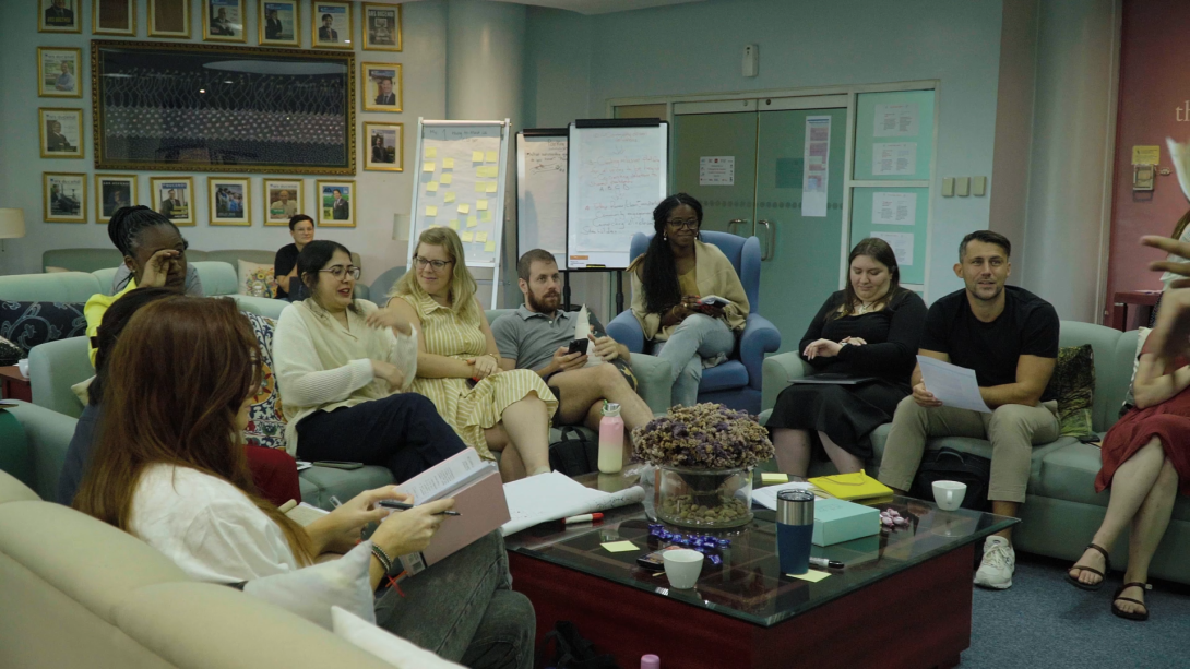 A diverse group of adults sit in a circle and are engaged in a dynamic conversation