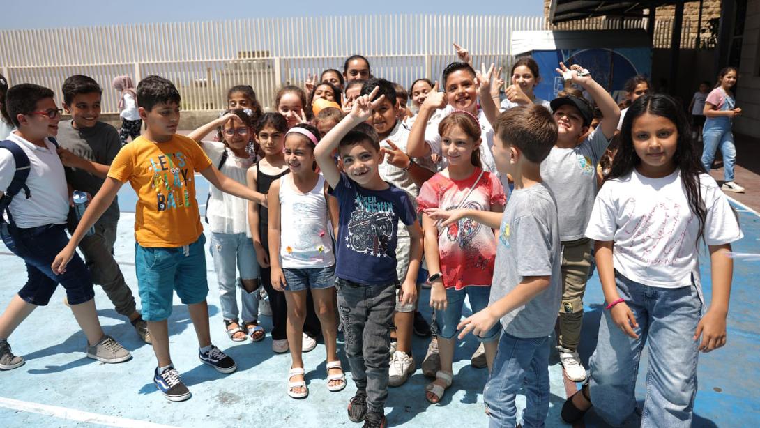 A large group of young Lebanese children pose for a photo in an outdoor courtyard smiling and laughing