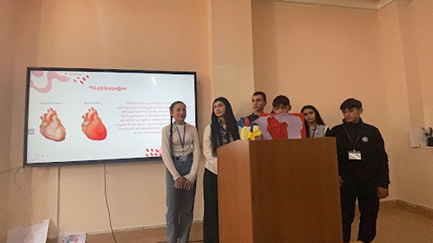 Students stand in front of a screen sharing a presentation about the heart