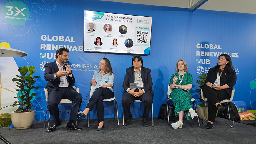 Two men in suits and three women in business clothing sit on a panel on a stage in front of a background that says Global Renewable Hub